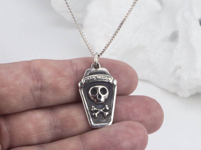 The Dead Inside pendant held between fingers to show its size